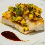 Tasty Wahoo Recipes to Impress Your Dinner Guests 2 A close-up of wahoo fish tacos topped with fresh cabbage, cilantro, and a drizzle of lime crema, served on a rustic plate.